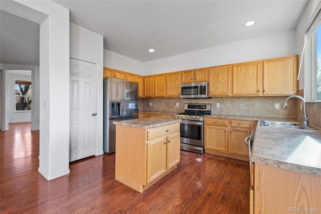 kitchen with appliances with stainless steel finishes, dark hardwood / wood-style flooring, backsplash, sink, and a center island