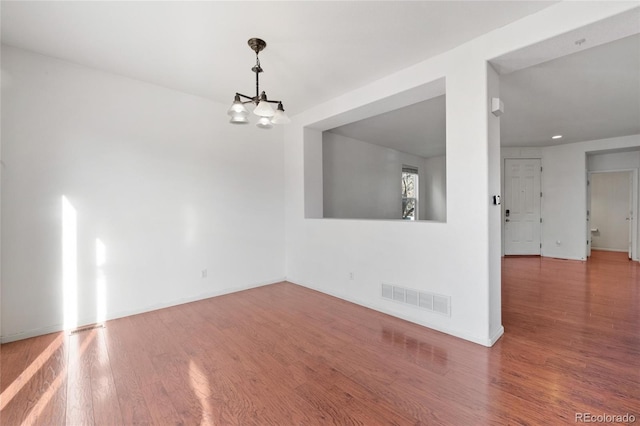 unfurnished room with wood-type flooring and an inviting chandelier