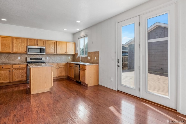 kitchen with sink, dark wood-type flooring, appliances with stainless steel finishes, and tasteful backsplash