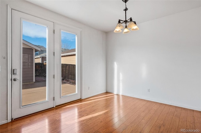 empty room with light hardwood / wood-style floors and a notable chandelier