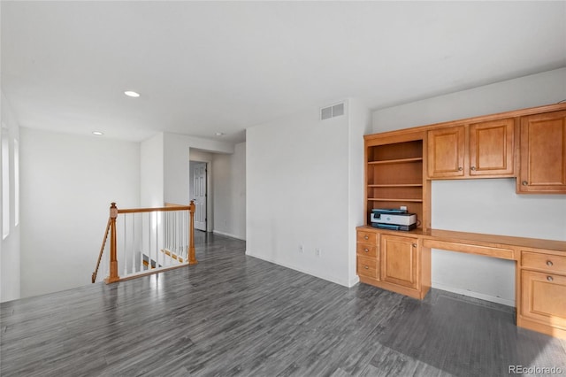 unfurnished office featuring dark hardwood / wood-style floors and built in desk