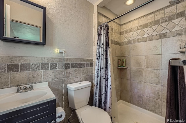 8600 W 2nd Ave, Lakewood, CO 80226 - bathroom featuring a textured wall, toilet, vanity, a stall shower, and tile walls