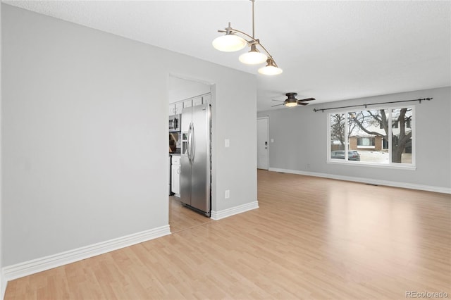 unfurnished living room featuring light wood-type flooring, ceiling fan, and baseboards