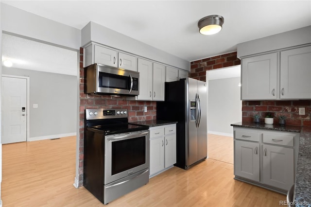 kitchen featuring baseboards, stainless steel appliances, light wood-style flooring, and gray cabinetry