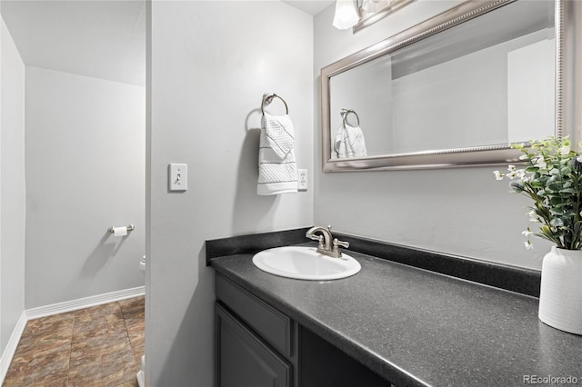 half bathroom with toilet, vanity, and baseboards