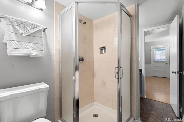 bathroom with tile patterned flooring, a shower stall, and toilet