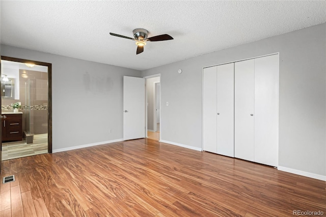 unfurnished bedroom featuring a textured ceiling, light wood finished floors, visible vents, and baseboards