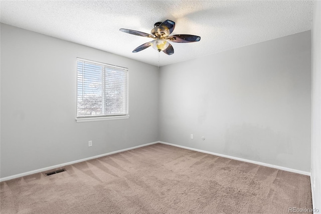 empty room featuring ceiling fan, a textured ceiling, visible vents, baseboards, and carpet