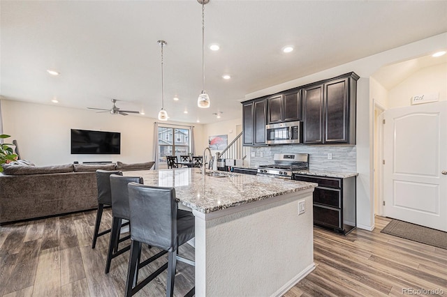 26385 E Canal Pl, Aurora, CO 80018 - kitchen with stainless steel appliances, a sink, recessed lighting, wood finished floors, and light stone countertops