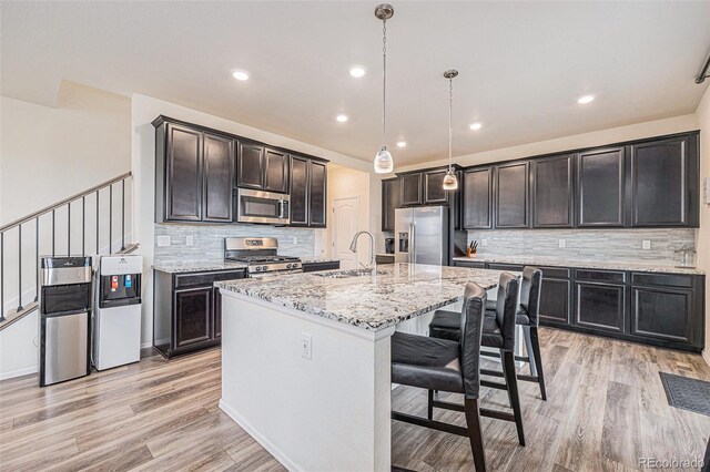 26385 E Canal Pl, Aurora, CO 80018 - kitchen with a sink, stainless steel appliances, light wood-style flooring, light stone countertops, and decorative backsplash