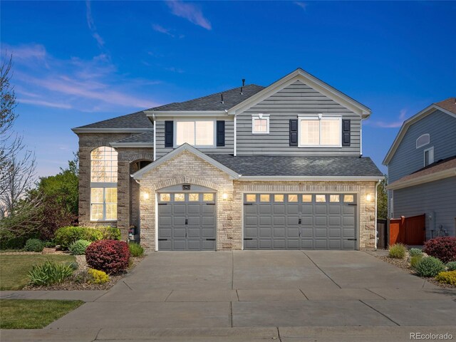 view of front of house with driveway, brick siding, an attached garage, and roof with shingles