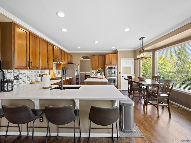 kitchen featuring a sink, light countertops, appliances with stainless steel finishes, backsplash, and crown molding