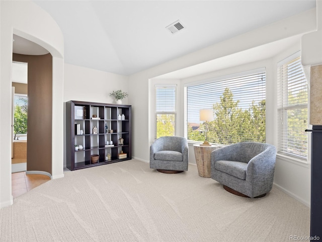 sitting room featuring carpet, arched walkways, baseboards, and vaulted ceiling