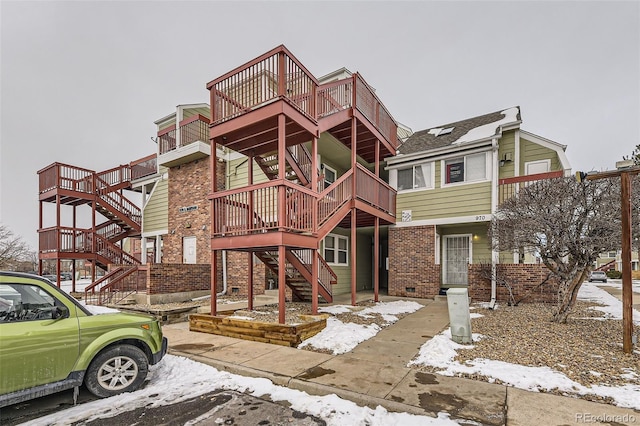 view of property featuring stairs and brick siding