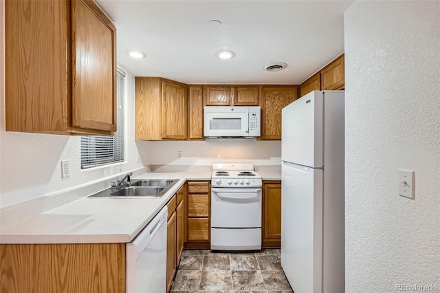 kitchen with white appliances, visible vents, brown cabinets, light countertops, and a sink