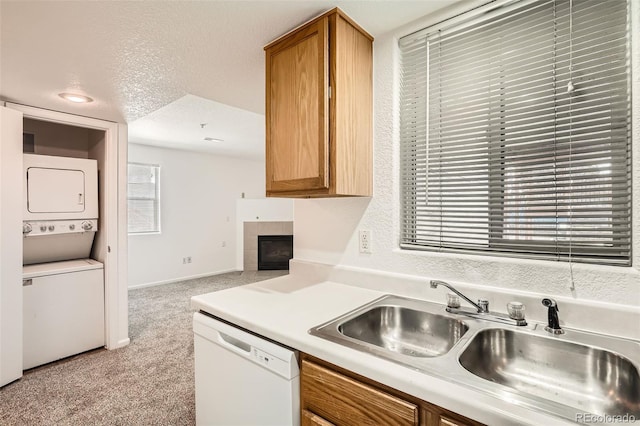 kitchen featuring white dishwasher, light colored carpet, stacked washer / dryer, a sink, and light countertops