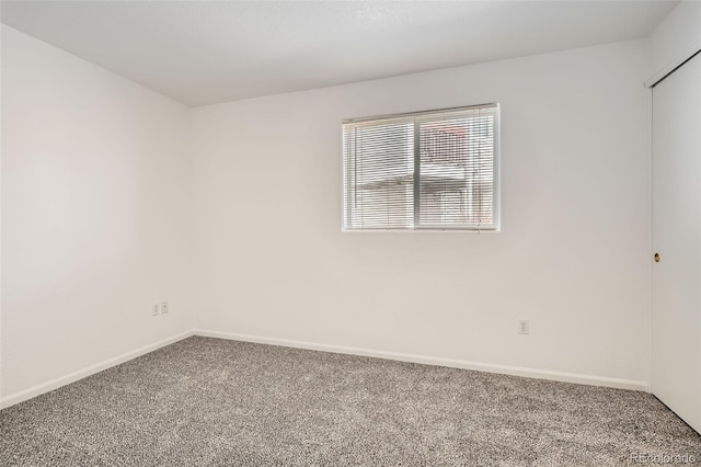 spare room featuring carpet floors and baseboards