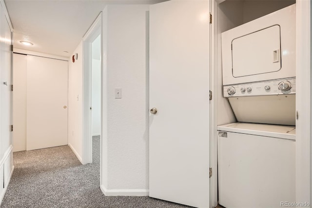 clothes washing area with laundry area, baseboards, and stacked washer and clothes dryer