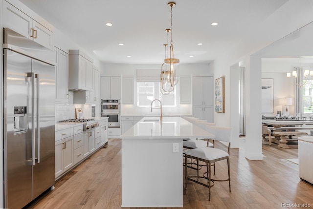 2141 Fountain Cir, Erie, CO 80516 - kitchen featuring appliances with stainless steel finishes, a chandelier, a sink, tasteful backsplash, and a center island with sink