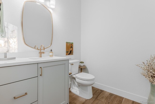 2141 Fountain Cir, Erie, CO 80516 - half bathroom featuring wood finished floors, toilet, vanity, and baseboards