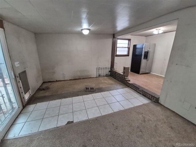 1078 Elmira St, Aurora, CO 80010 - basement featuring stainless steel fridge with ice dispenser, carpet flooring, and tile patterned floors