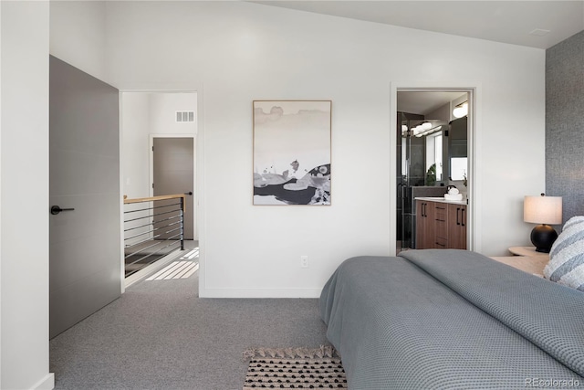 bedroom featuring ensuite bathroom, carpet flooring, and vaulted ceiling