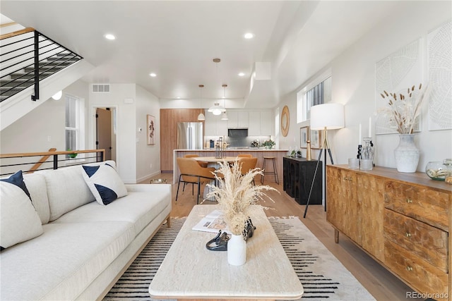 living room featuring recessed lighting, visible vents, light wood-type flooring, and baseboards