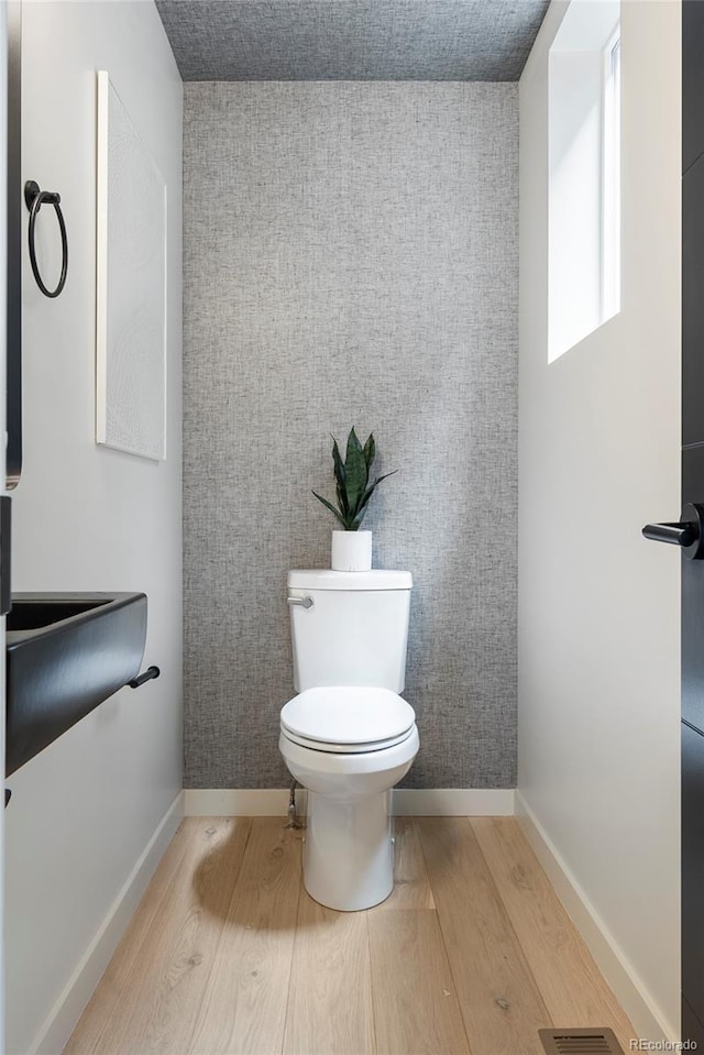 1262 N Stuart St Unit 2, Denver, CO 80204 - half bathroom featuring wood finished floors, toilet, an accent wall, and baseboards