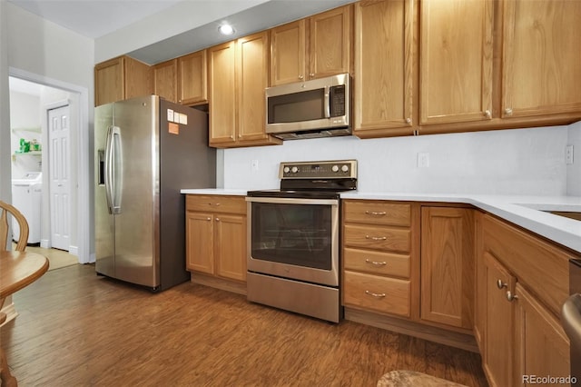 3325 W 111th Loop Unit C, Westminster, CO 80031 - kitchen featuring appliances with stainless steel finishes, wood finished floors, washing machine and clothes dryer, and light countertops