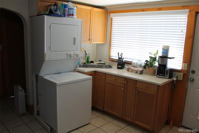 933 Skeel St, Brighton, CO 80601 - laundry area featuring stacked washer and clothes dryer, healthy amount of natural light, light tile patterned flooring, and arched walkways