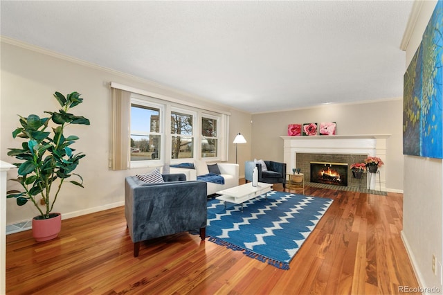 living room with wood-type flooring, crown molding, and a brick fireplace