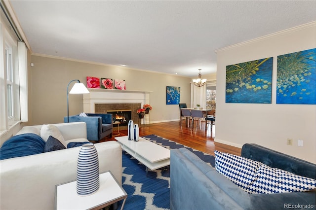 living room featuring a tiled fireplace, hardwood / wood-style flooring, ornamental molding, a textured ceiling, and a chandelier