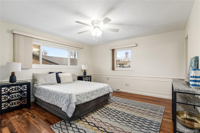 bedroom with multiple windows, ceiling fan, dark hardwood / wood-style flooring, and a textured ceiling