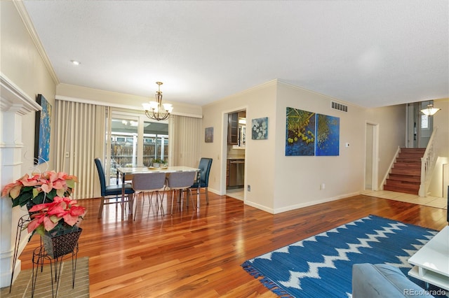 dining room featuring a chandelier, hardwood / wood-style floors, a textured ceiling, and crown molding