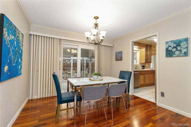 dining room featuring crown molding, an inviting chandelier, a textured ceiling, and light wood-type flooring