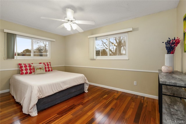 bedroom with multiple windows, ceiling fan, dark wood-type flooring, and a textured ceiling