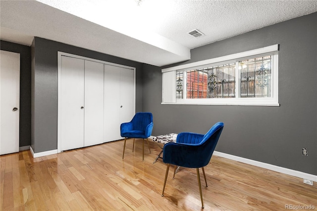 living area with a textured ceiling and light wood-type flooring