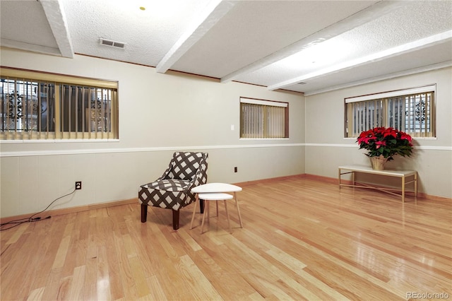 unfurnished room with beamed ceiling, a textured ceiling, and hardwood / wood-style flooring