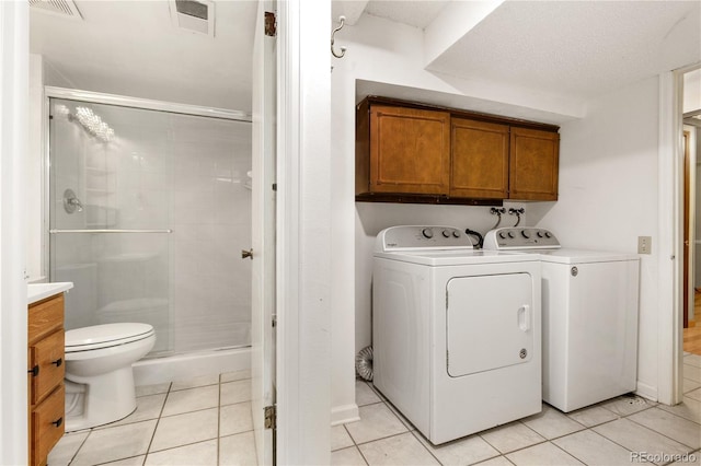 laundry room with washer and clothes dryer, light tile patterned floors, and a textured ceiling