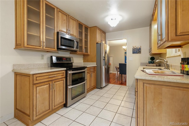 kitchen with appliances with stainless steel finishes, light stone countertops, sink, and light tile patterned floors