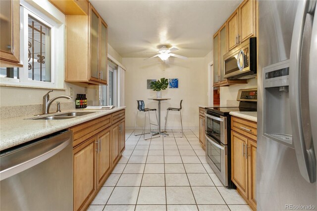 kitchen with stainless steel appliances, sink, light tile patterned floors, and ceiling fan