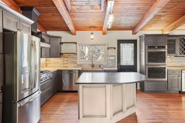 kitchen featuring decorative backsplash, stainless steel appliances, beamed ceiling, a kitchen island, and hanging light fixtures