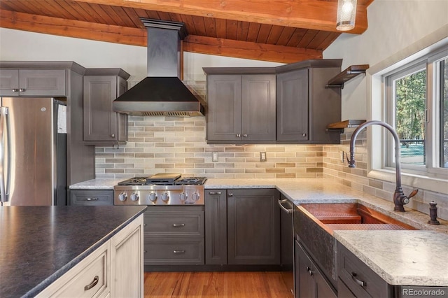 kitchen featuring decorative backsplash, appliances with stainless steel finishes, wall chimney range hood, wooden ceiling, and vaulted ceiling with beams