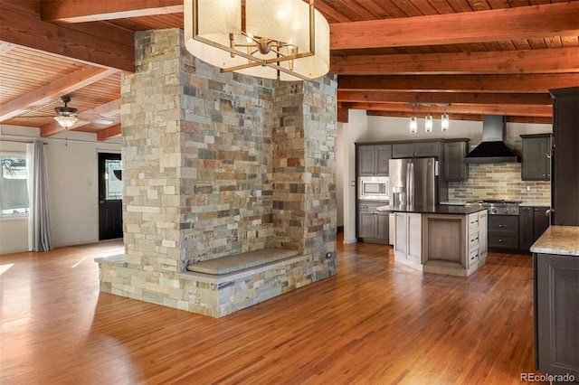 kitchen featuring beam ceiling, a center island, stainless steel appliances, decorative light fixtures, and custom range hood