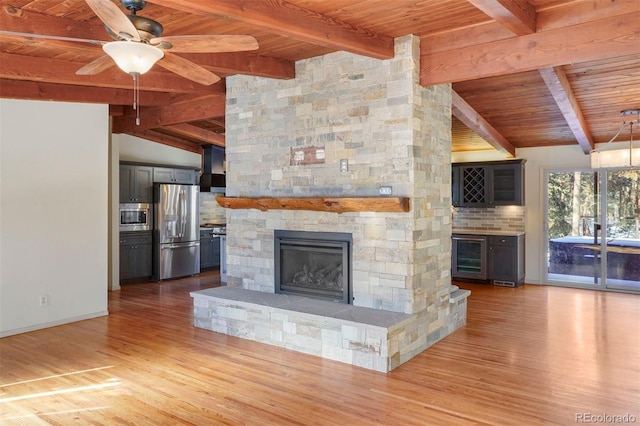 unfurnished living room with ceiling fan, lofted ceiling with beams, wooden ceiling, a fireplace, and hardwood / wood-style floors