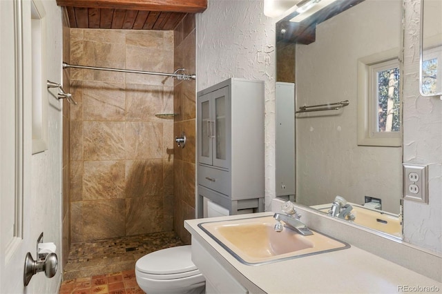 bathroom featuring a tile shower, toilet, and sink