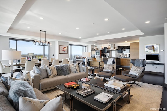 living room with a raised ceiling and a notable chandelier