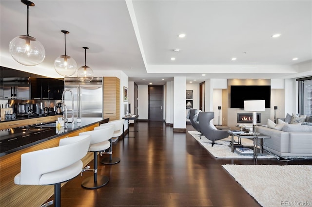 interior space with stainless steel built in fridge, pendant lighting, sink, and dark wood-type flooring