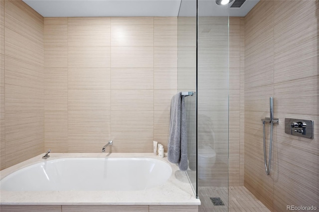 bathroom featuring separate shower and tub and tile walls