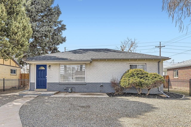 bungalow featuring brick siding, a shingled roof, and fence